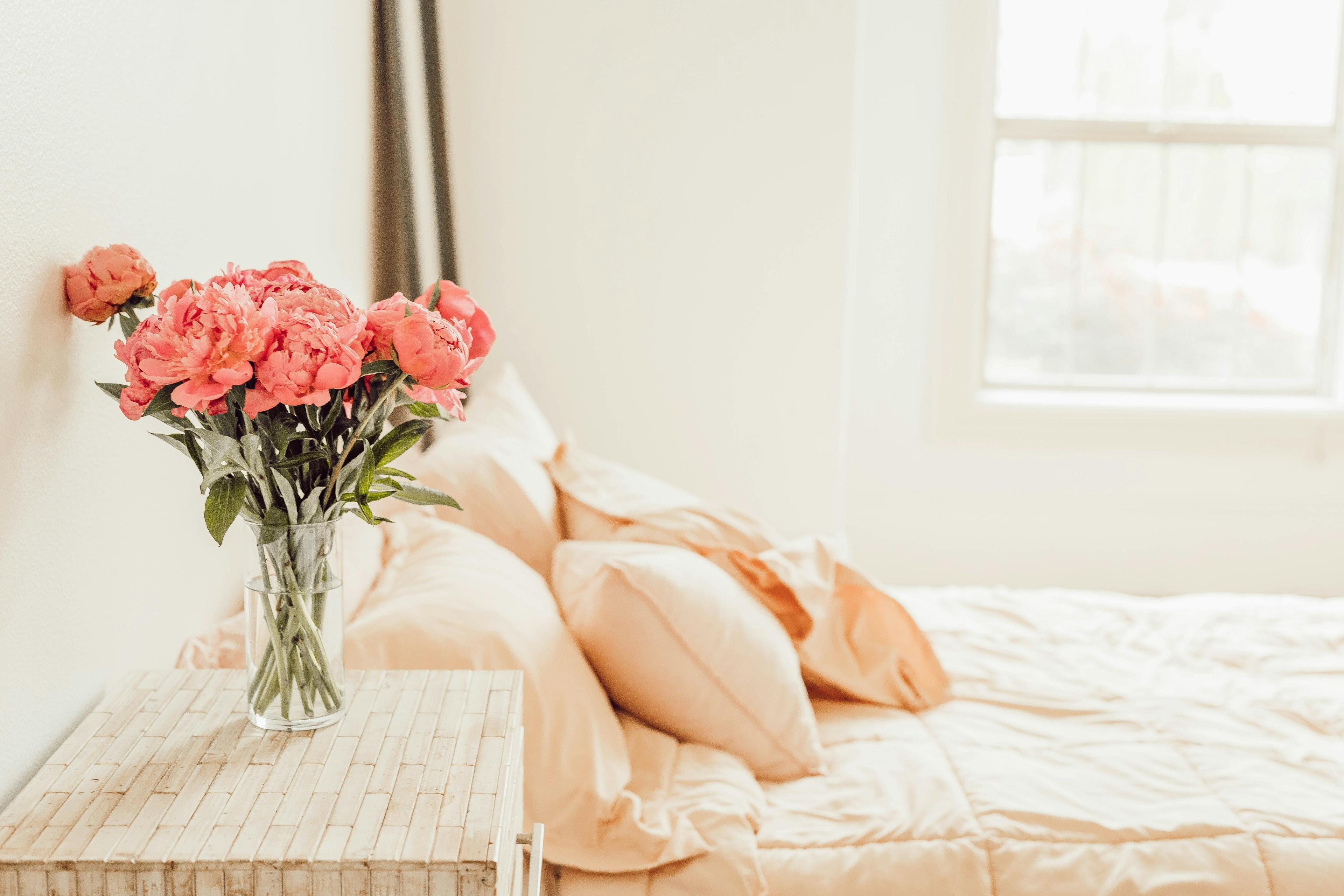 pink flowers on a bedside beside a bed